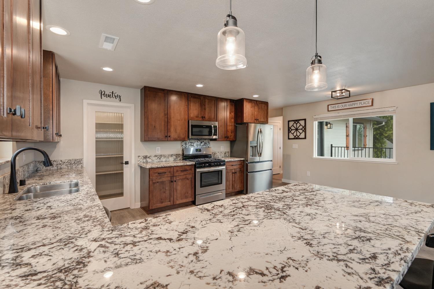 314 East Main Street Ione, CA 95640 - Photo 20 of 43 a kitchen with stainless steel appliances granite countertop a refrigerator a stove a sink dishwasher a oven with white cabinets and wooden floor