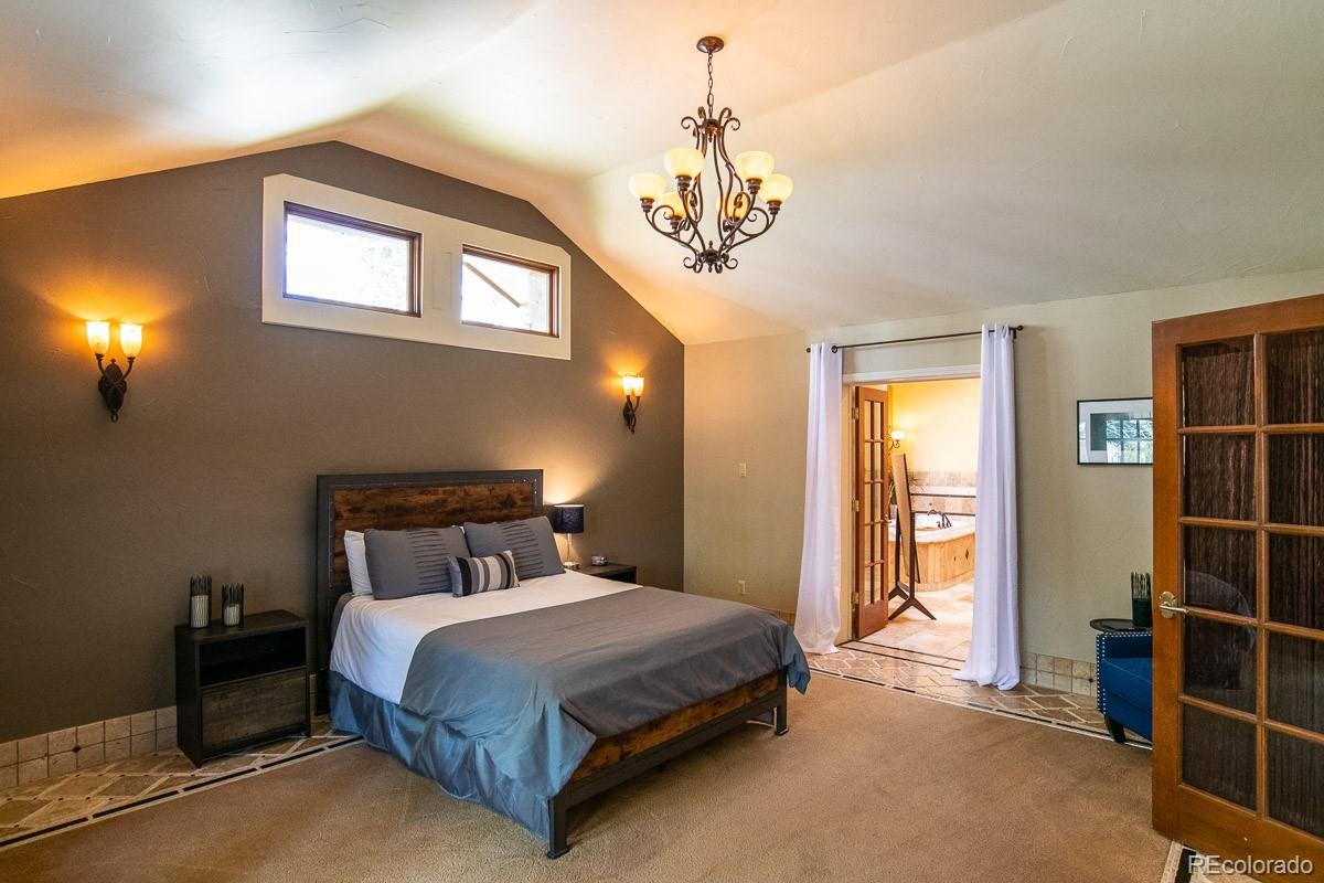 7181 Four Rivers Road Boulder, CO 80301 - Photo 16 of 35 a bedroom with a bed and a chandelier