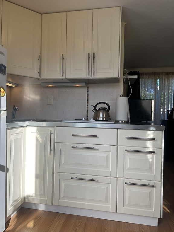 174 Captain Chase Road, Unit 9 Dennis, MA 02639 - Photo 4 of 23 a kitchen with white cabinets and a stove