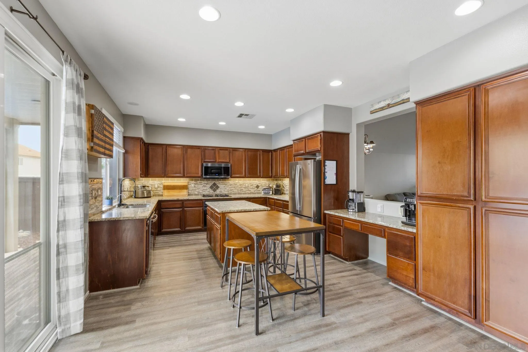 31342 Euclid Loop Winchester, CA 92596 - Photo 19 of 50 a kitchen with stainless steel appliances kitchen island granite countertop a refrigerator a stove a sink a dining table and chairs with wooden floor