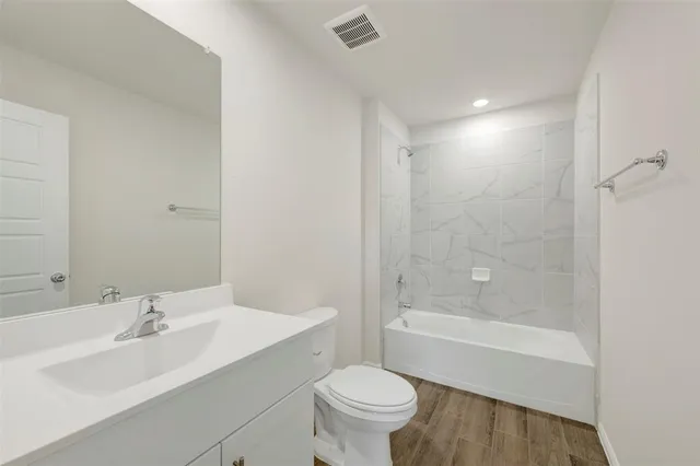 a bathroom with a bathtub shower sink vanity mirror and toilet