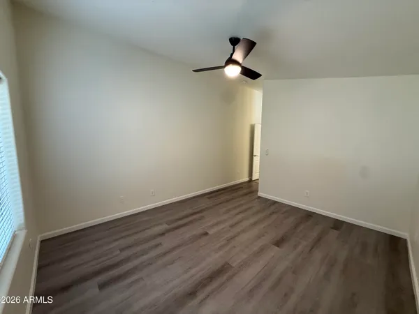 an empty room with wooden floor chandelier fan and windows