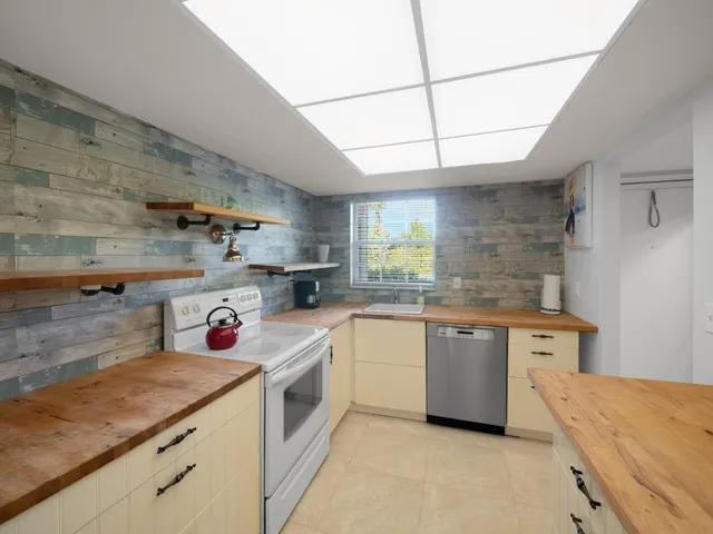 a kitchen with a sink dishwasher stove and white cabinets