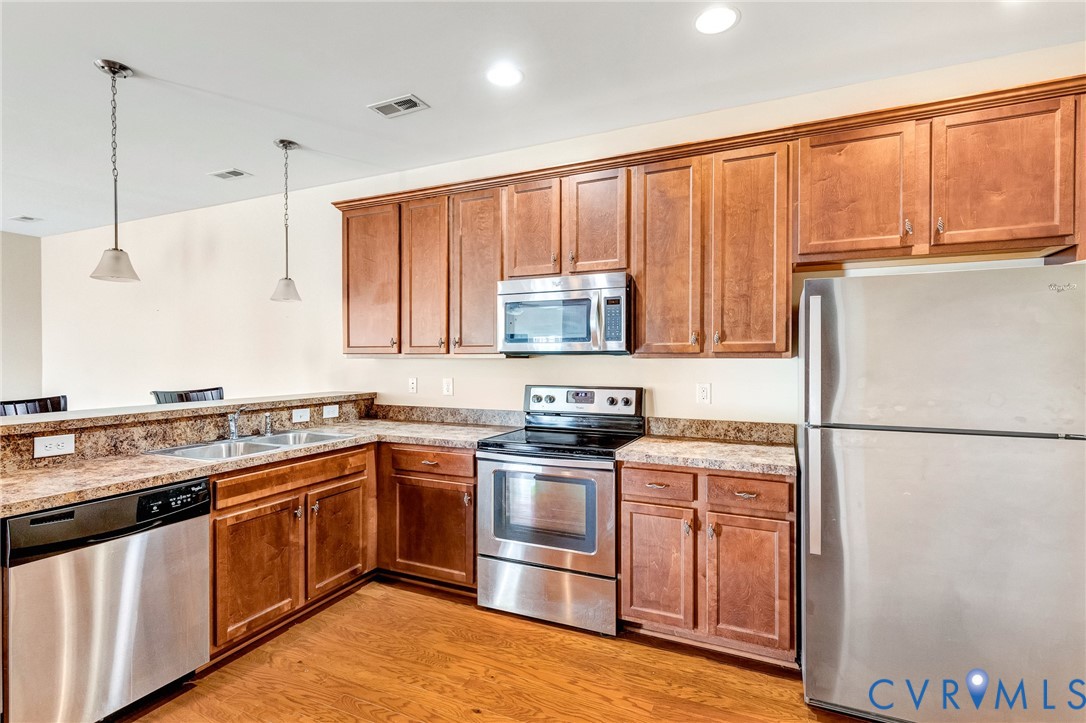 8996 Brigadier Road, Unit 4A Mechanicsville, VA 23116 - Photo 17 of 35 a kitchen with stainless steel appliances granite countertop a refrigerator a sink dishwasher a stove with large countertops with wooden floor