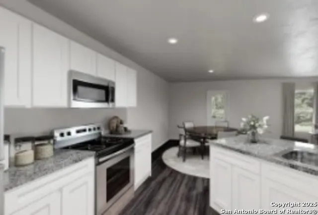 a kitchen with granite countertop a sink a stove and cabinets