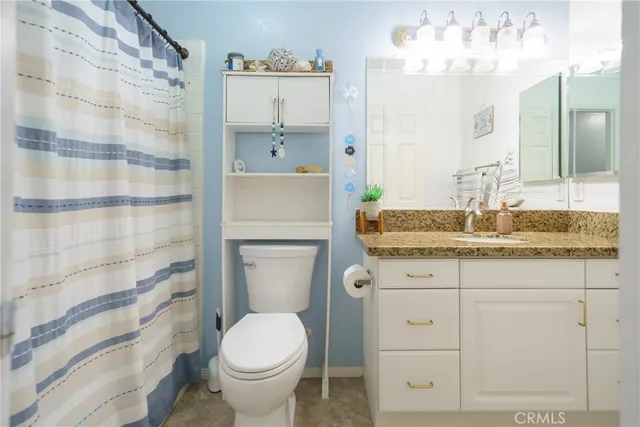 a bathroom with a granite countertop toilet sink and mirror