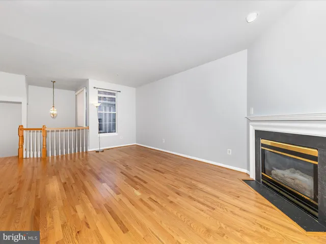 a view of an empty room with wooden floor fireplace and a window