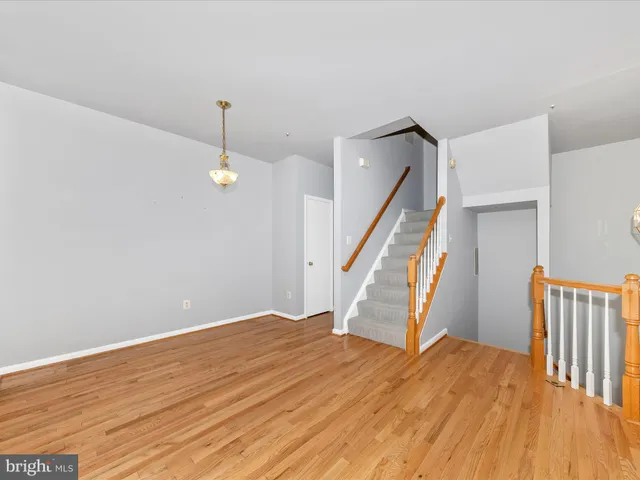 a view of an empty room with wooden floor and stairs