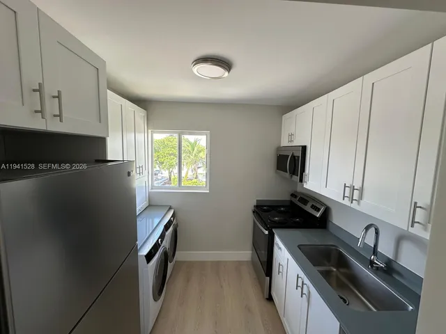 a kitchen with a sink a refrigerator and cabinets