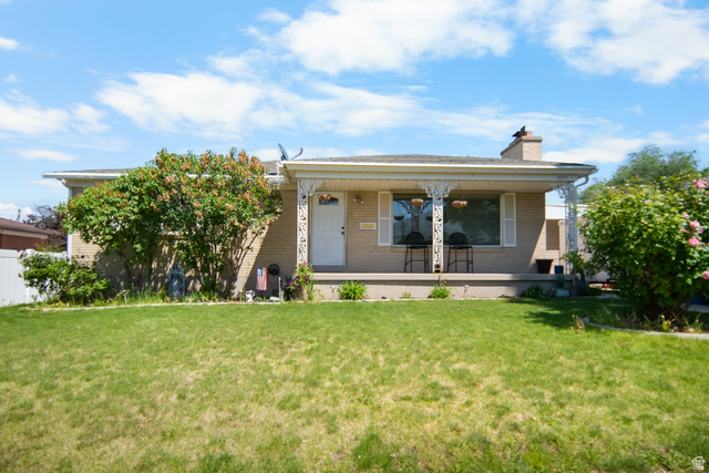 3233 Jean Street Magna, UT 84044 - Photo 1 of 33 Brick exterior with a covered porch featuring decorative metalwork, a white entry door, and a prominent front-facing chimney