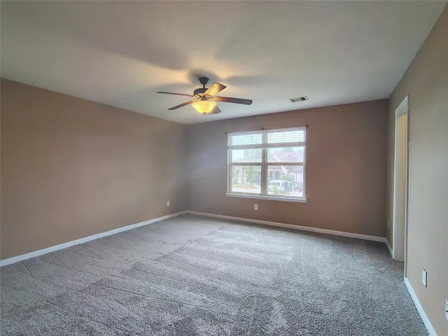 an empty room with windows and chandelier fan