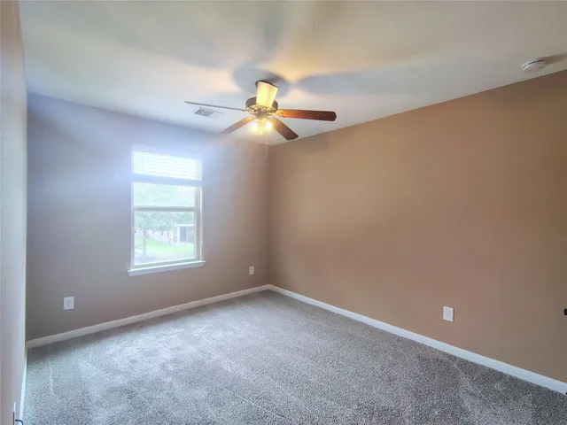 an empty room with a window and a fan