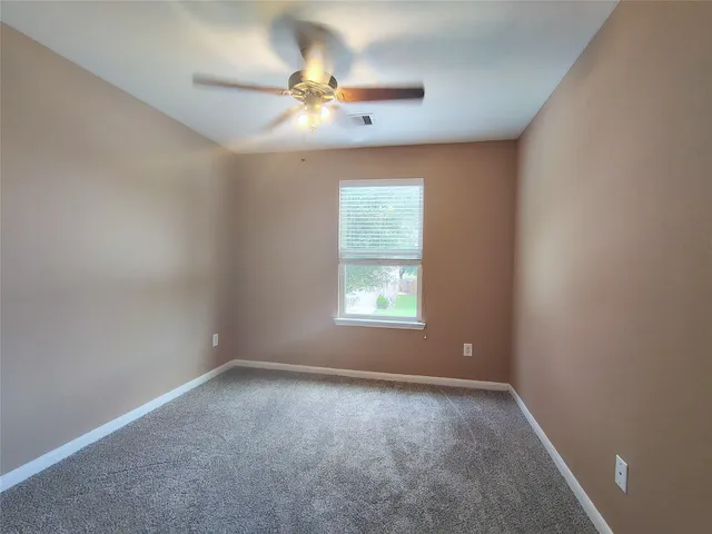en empty room with windows and chandelier fan