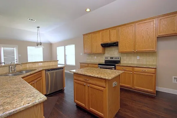 a kitchen with granite countertop a sink a counter top space and cabinets