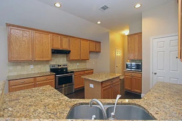 a kitchen with stainless steel appliances granite countertop a sink stove and refrigerator