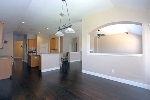 a view of a big room with wooden floor and a kitchen