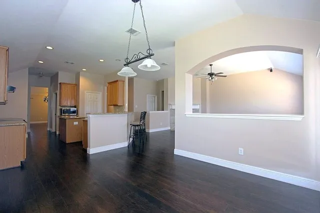 a view of a big room with wooden floor and a kitchen