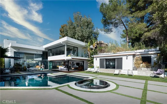 a view of swimming pool with seating area and trees in the background