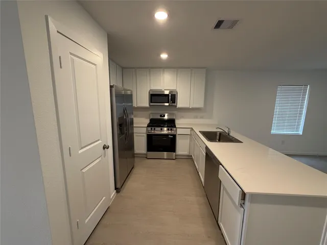 a kitchen with granite countertop white cabinets and refrigerator
