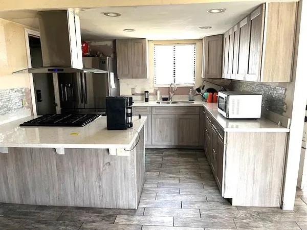 a kitchen with kitchen island granite countertop a refrigerator and a sink