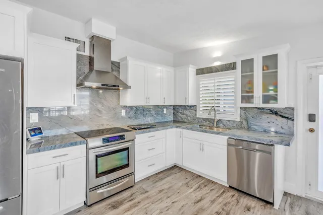a kitchen with stainless steel appliances granite countertop a sink stove and cabinets