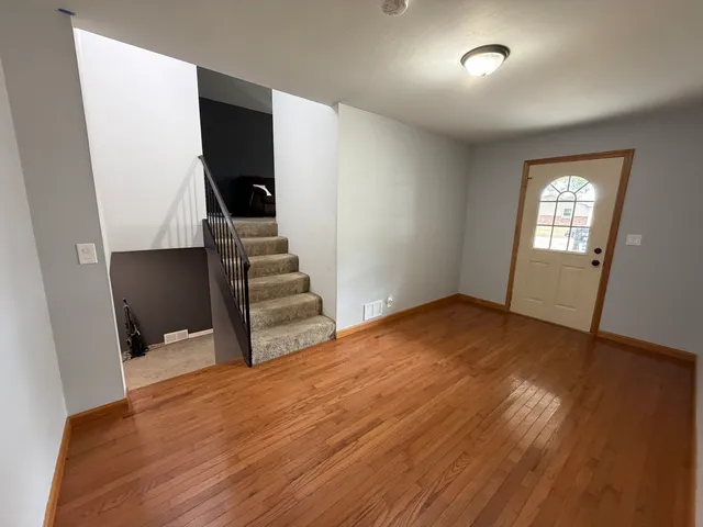 an empty room with wooden floor and staircase