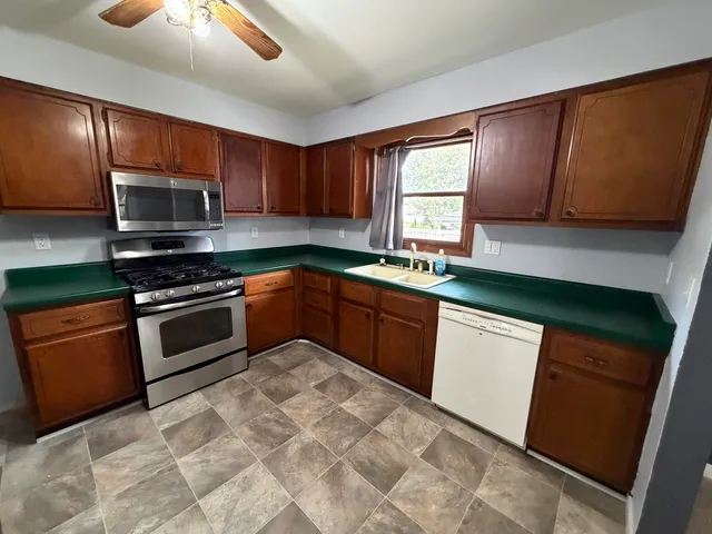 a kitchen with stainless steel appliances granite countertop wooden cabinets a stove top oven a sink and dishwasher