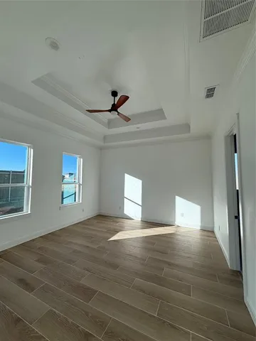 a view of empty room with wooden floor and fan