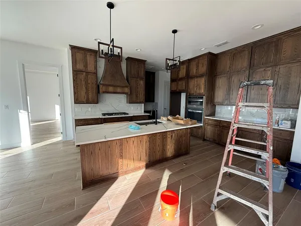 a kitchen with stainless steel appliances kitchen island granite countertop a stove a refrigerator and a wooden cabinets