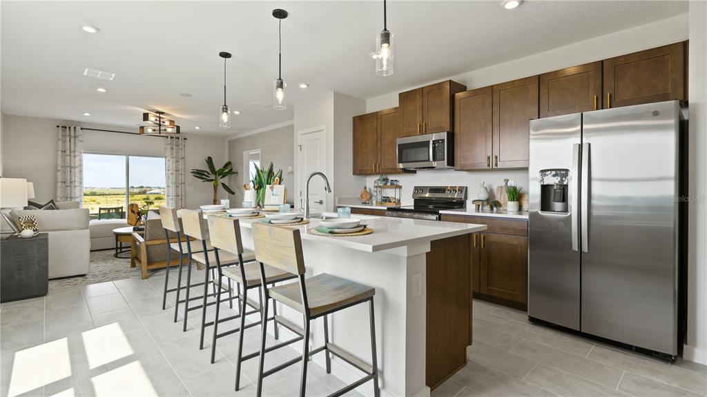 1353 June Lake Loop Haines City, FL 33844 - Photo 17 of 44 a kitchen with stainless steel appliances kitchen island granite countertop a refrigerator a stove a sink a dining table and chairs with wooden floor