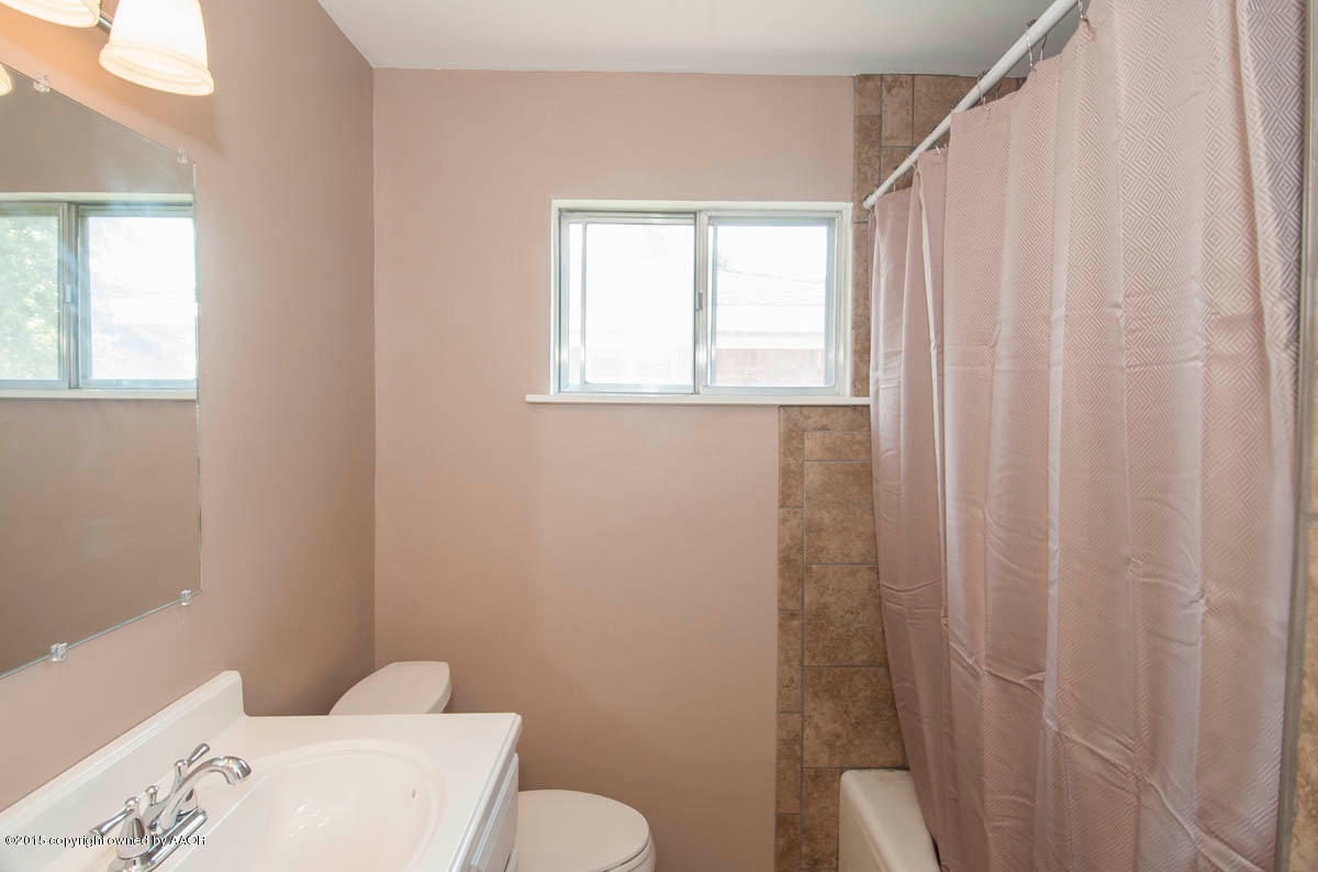 6016 Gainsborough Road Amarillo, TX 79106 - Photo 23 of 36 a bathroom with a toilet and a shower curtain