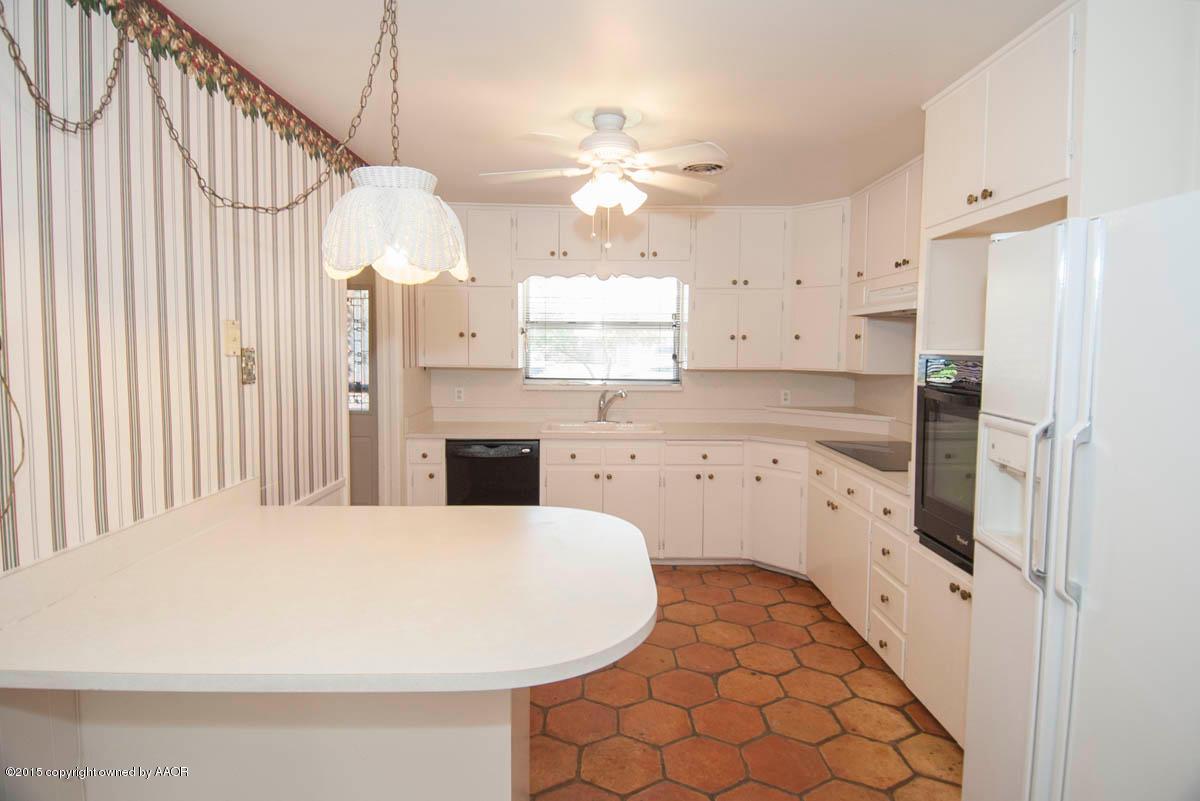 6016 Gainsborough Road Amarillo, TX 79106 - Photo 8 of 36 a kitchen with stainless steel appliances a white refrigerator a sink dishwasher a dining table and chairs with wooden floor