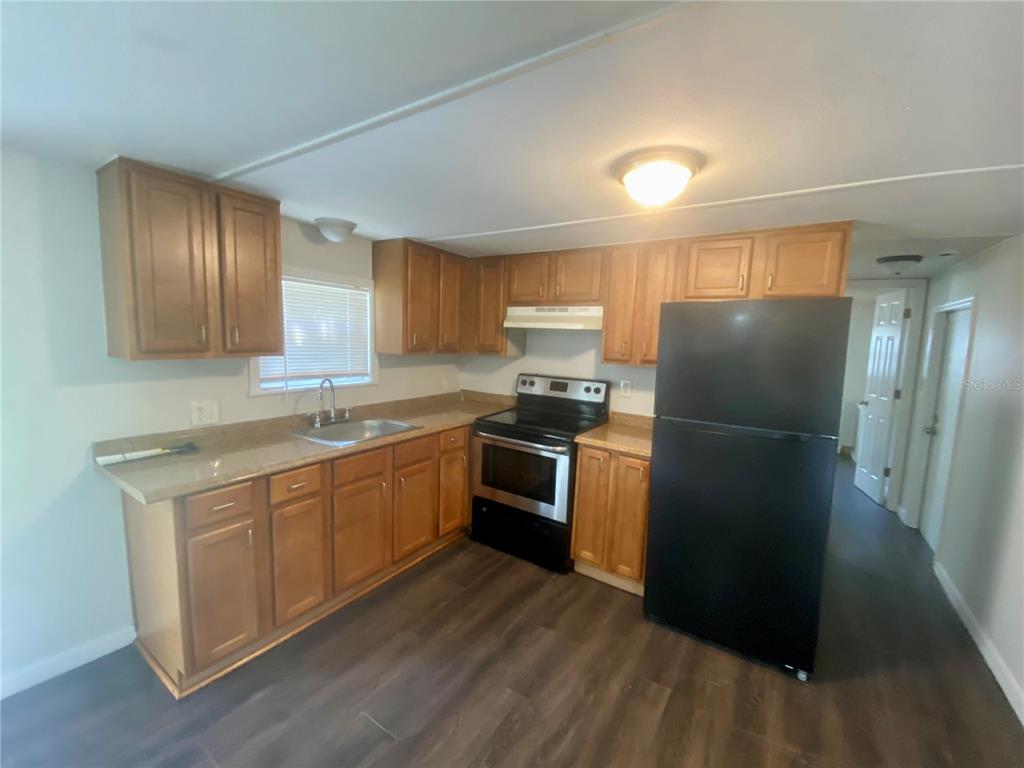 38313 Tucker Road, Unit 3 Zephyrhills, FL 33542 - Photo 9 of 20 a kitchen with a refrigerator and a sink
