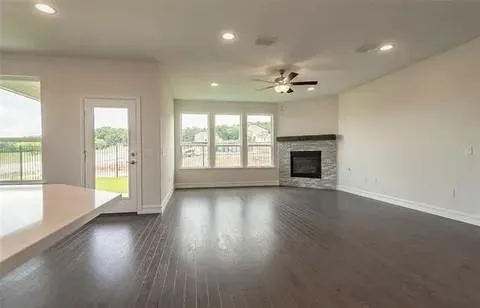 an empty room with wooden floor fireplace and windows
