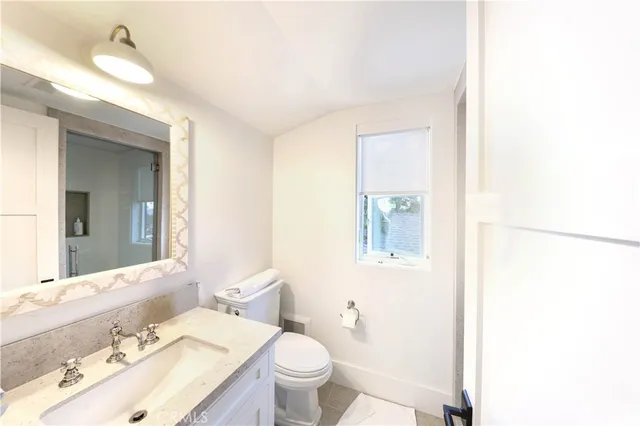 a bathroom with a granite countertop sink mirror vanity and toilet