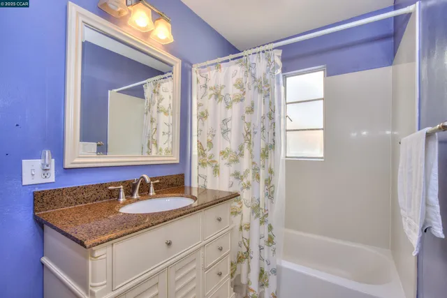 a bathroom with a granite countertop sink a mirror and a bathtub