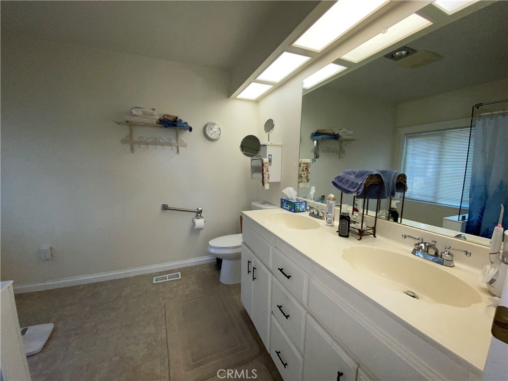 9607 Rosedale Drive Calimesa, CA 92320 - Photo 21 of 27 a bathroom with a double vanity sink toilet and a mirror