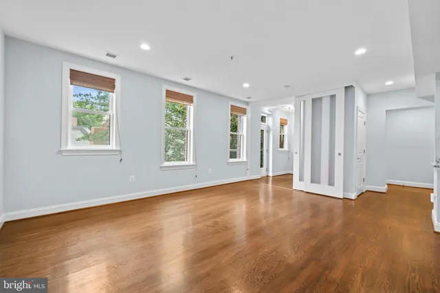 a view of an empty room with wooden floor and a window