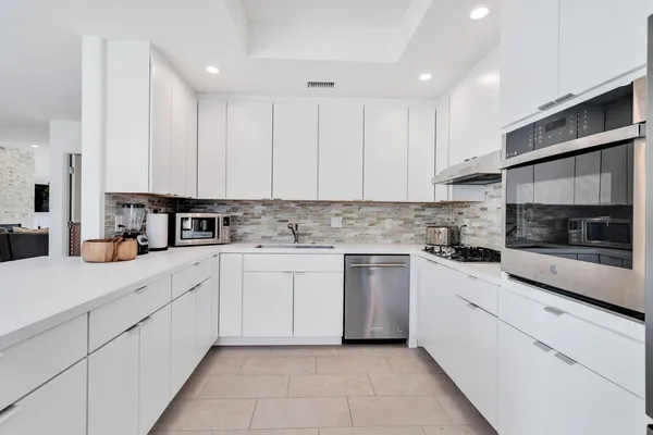 a kitchen with granite countertop white cabinets and white appliances