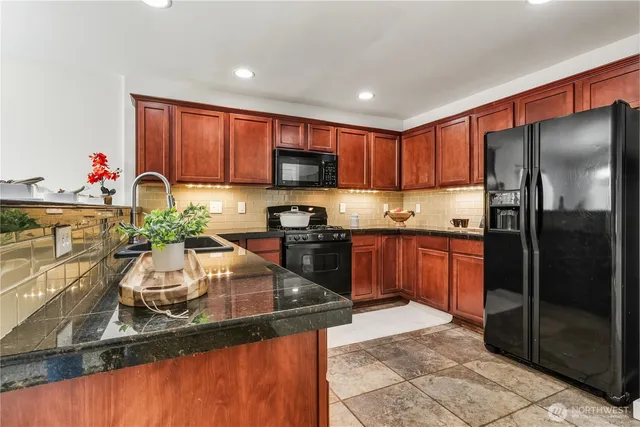a kitchen with stainless steel appliances granite countertop a sink refrigerator and cabinets