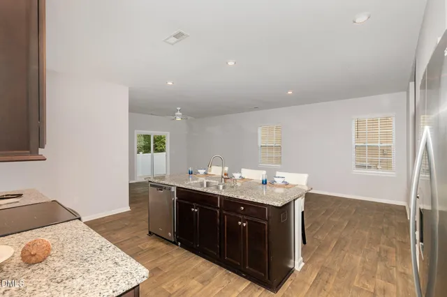 a kitchen with kitchen island granite countertop wooden floors a stove and a refrigerator