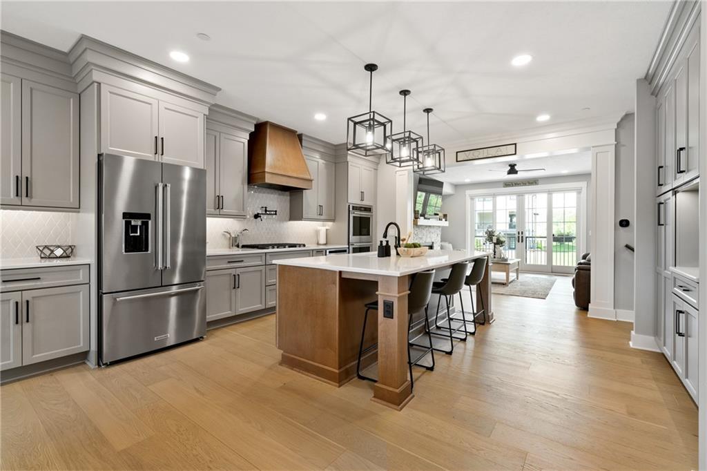 146 Enclave Drive Mars, PA 16046 - Photo 8 of 43 a kitchen with kitchen island a refrigerator a stove a dining table and chairs with wooden floor
