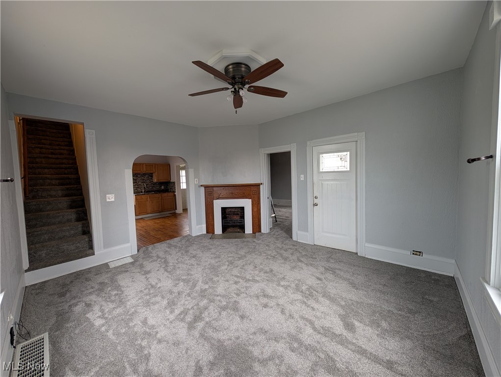 10143 Pleasant Road Pleasant City, OH 43772 - Photo 3 of 32 Unfurnished living room featuring a fireplace, arched walkways, light carpet, and a ceiling fan