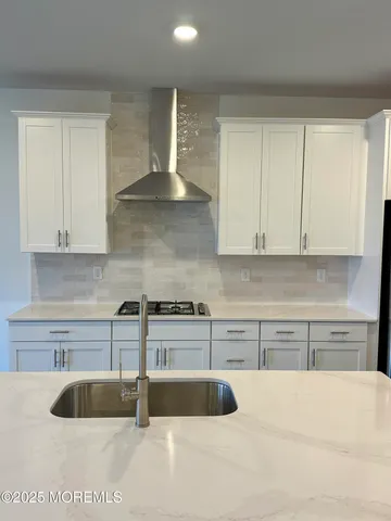 a kitchen with granite countertop a sink a stove and cabinets