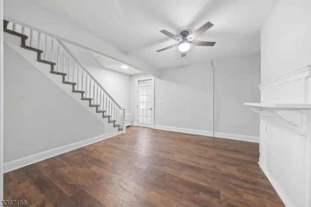 a view of an empty room with wooden floor and staircase