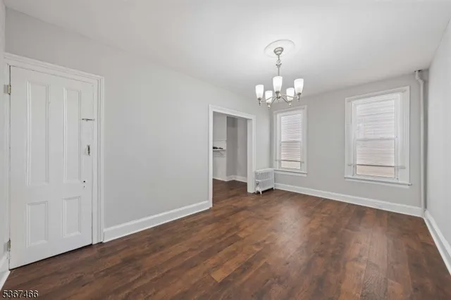 a view of an empty room with wooden floor and windows