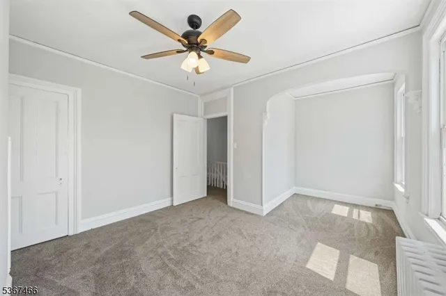 an empty room with a ceiling fan and carpet