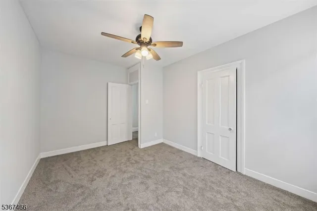 an empty room with a chandelier fan and closet