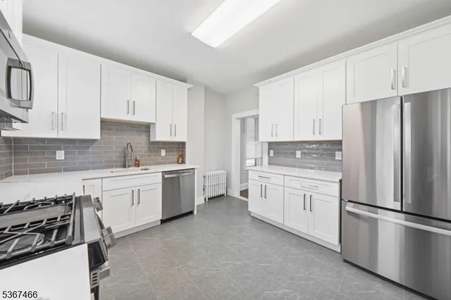 a kitchen with granite countertop white cabinets and stainless steel appliances