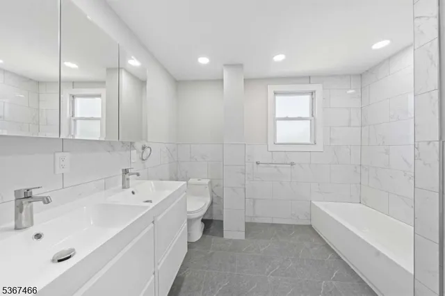 a bathroom with a bathtub a sink a toilet and mirror